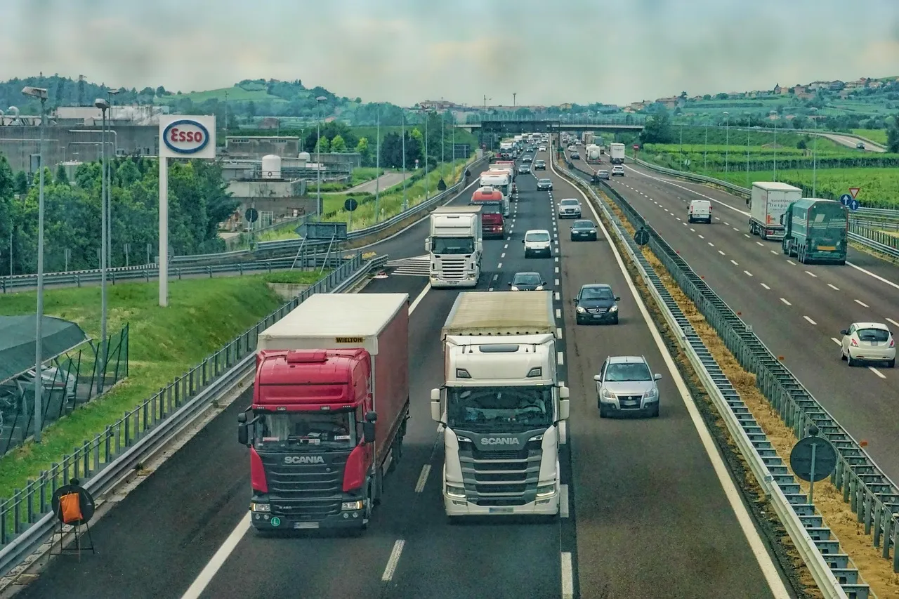 Rodovia com tráfego de caminhões e veículos em dia ensolarado.