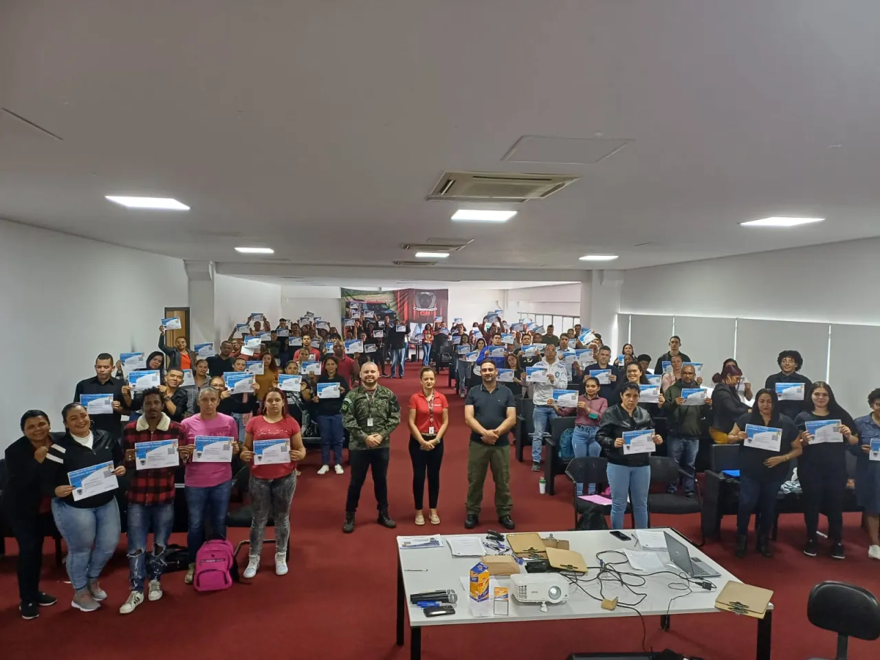 Instrutor Bruno Moisés em curso de formação com alunos levantando seus certificados