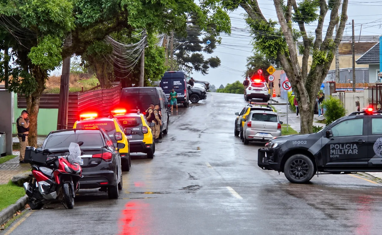 Viaturas e agentes de segurança em rua molhada durante a operação no entorno do CMEI São Braz, em Curitiba.