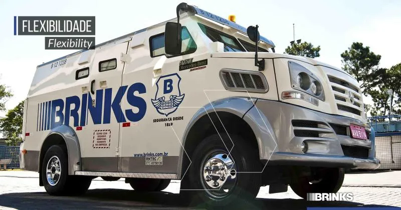 Carro-forte branco da Brink’s estacionado em uma base da empresa, ilustrando a logística segura e o transporte de valores.